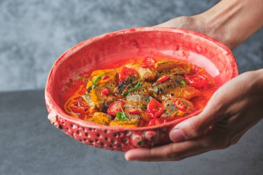Elleri tabakta, soslu yılan balığı ve kırmızı biber.