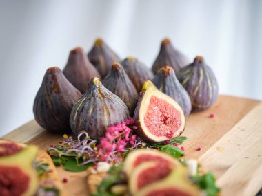 Bütünü kapatın ve ağaç tepsiye yerleştirilmiş incir dilimlenmiş meyve, peynir ve salata ile birlikte koyun.