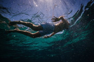 Yaz tatilinde mavi denizde yüzen dalgıç maskeli bir çocuktan.