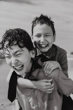 Siyah beyaz, üniformalı, küçük kardeşini sırtında taşıyan, gözleri kapalı bir çocuk.