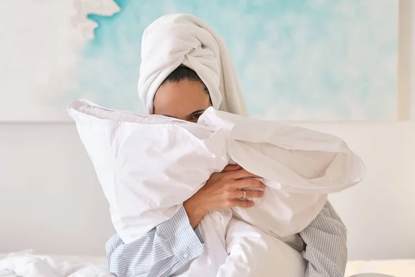 Женщина Полотенцем Голове Прячется Лицом Белыми Подушками Сидя Кровати Спальне — стоковое фото