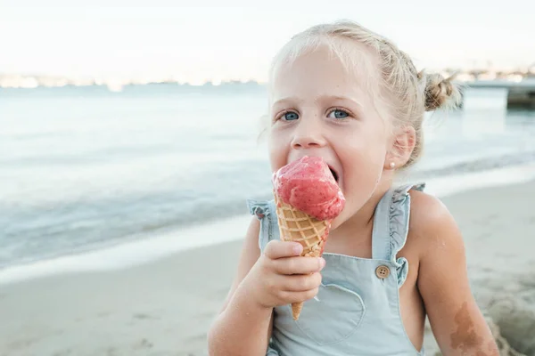Очаровательная Маленькая Девочка Ест Сладкое Мороженое Смотрит Камеру Сидя Песчаном — стоковое фото