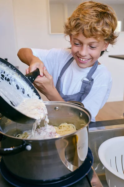 Cheerful Child Pan Adding Creamy Sauce Bacon Cooked Pasta Pot — Stock Photo, Image