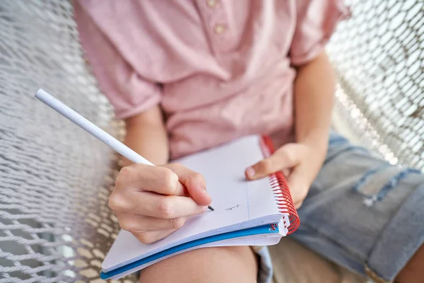 Unrecognizable Kid Casual Clothes Sitting Knitted Hammock Writing Notebook Pencil — Stock Photo, Image