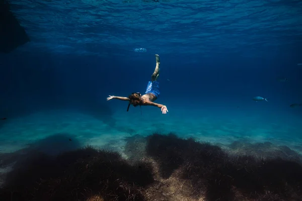 スノーケリングマスクと海底や魚のサンゴと青い海の下に浮かぶチューブで認識できない子供の完全な体 — ストック写真