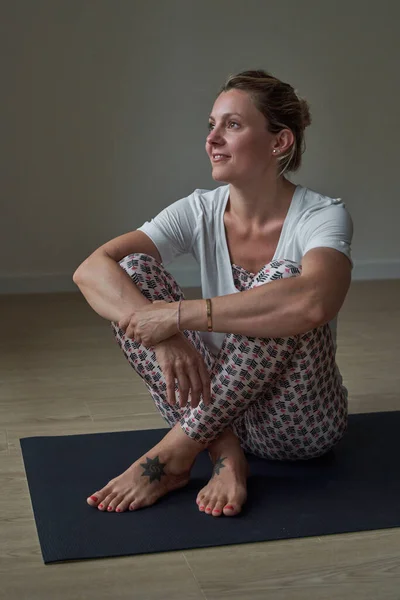 身穿运动服的全身上下都是积极的女性 她们坐在练习席上 在练习室照顾瑜伽 — 图库照片