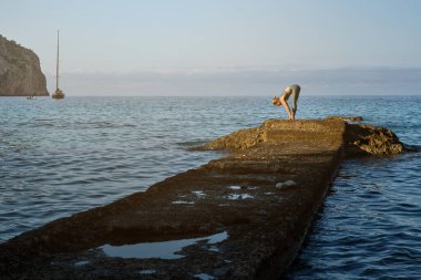 Anonim fit kadın fitness eğitimi sırasında taş iskelede öne eğilme egzersizi yapıyor.