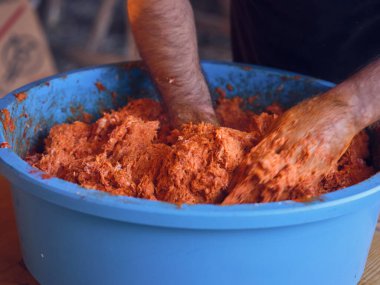 Meçhul erkek kasap mezbahada çalışırken mavi kasede sosis için kıyma yapıyor.