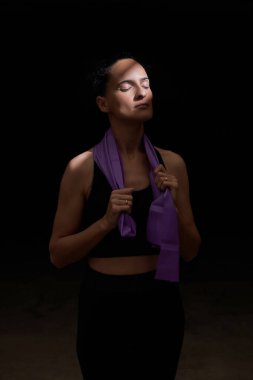 Hayalperest bayan sporcu gözleri kapalı elastik bandı boynuna dolayıp karanlık odada dinleniyor.