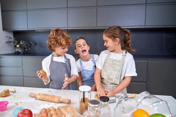 Veselé Děti Zástěrách Hnětení Těsta Sušenky Špinavého Stolu Různými Ingrediencemi — Stock fotografie