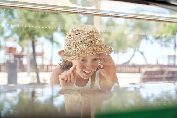 Hasır Şapkalı Neşeli Kıvırcık Çocuk Cam Manzaralı Şeffaf Vitrin Kenarında — Stok fotoğraf