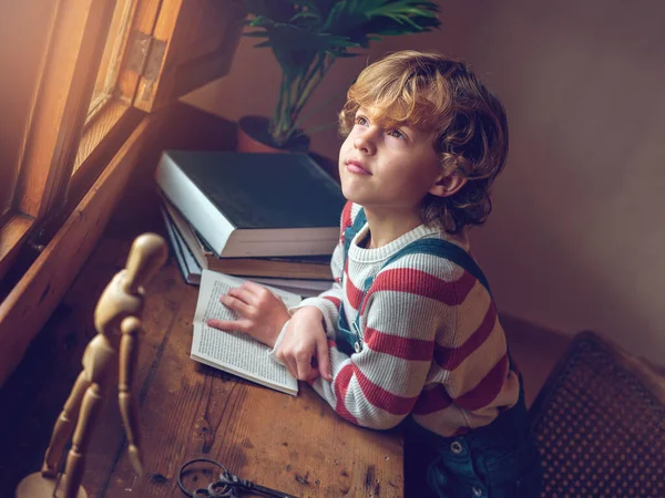 Malý Chlapec Sedí Dřevěného Stolu Zasněně Vzhlíží Zatímco Čte Školní — Stock fotografie