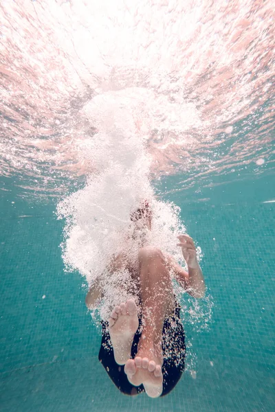 水中フルボディショット 水泳ショートパンツを着用している認識できない裸足の子供 プールの透明なきれいな青い水に飛び込む子供 — ストック写真