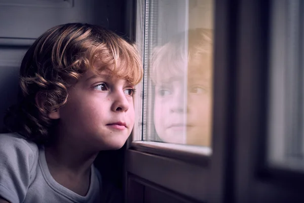 窓に傾いているかわいいブロンドの髪と愛らしいペンギンの小さな男の子は 自宅で夢見て — ストック写真