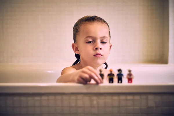 Poważny Chłopiec Mokrymi Włosami Bawiący Się Zabawkami Siedząc Białej Wannie — Zdjęcie stockowe