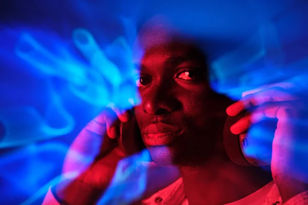 Afroameričtí Muži Jasně Zářících Neonových Světlech Poslouchají Hudbu Sluchátkách Dívají — Stock fotografie
