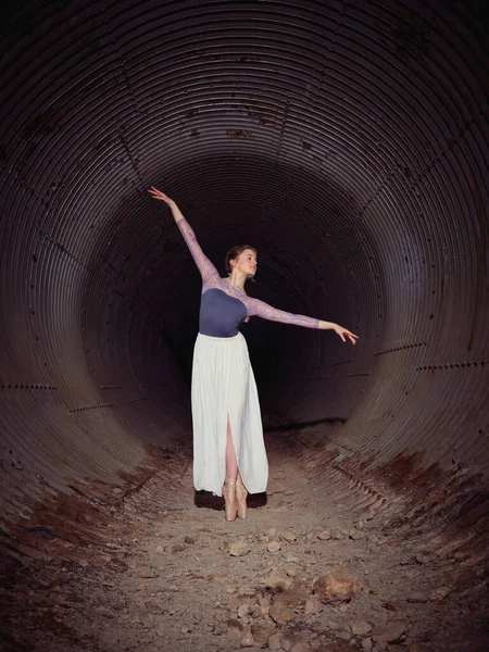 全身上下都是才华横溢的女芭蕾舞蹈家 穿着尖鞋 高举着胳膊 在老旧的有风风化墙壁的隧道里跳舞 — 图库照片