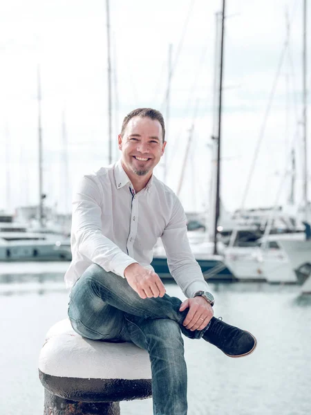 Positive Man Sitting Mooring Bollard Coast Harbor Yachts Smiling Camera — Stock Photo, Image