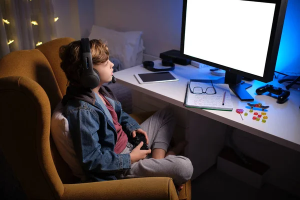 Kulaklıklı Çocuk Bilgisayar Monitörü Kumandayla Masada Otururken Video Oyunu Oynuyor — Stok fotoğraf