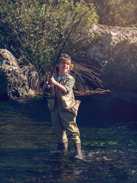 全副武装的男孩站在自然近岸的河里 用钓竿捕鱼 — 图库照片