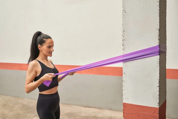 现代健身中心训练中用紫色阻带包裹柱头抽吸肌肉的女运动员的侧视图 — 图库照片