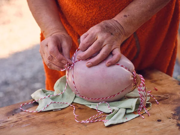 マヨルカの晴れた日に肉屋で働いている間 新鮮な伝統的なそばそばダソーセージを結ぶエプロンで認識できない成熟した女性を作ります — ストック写真