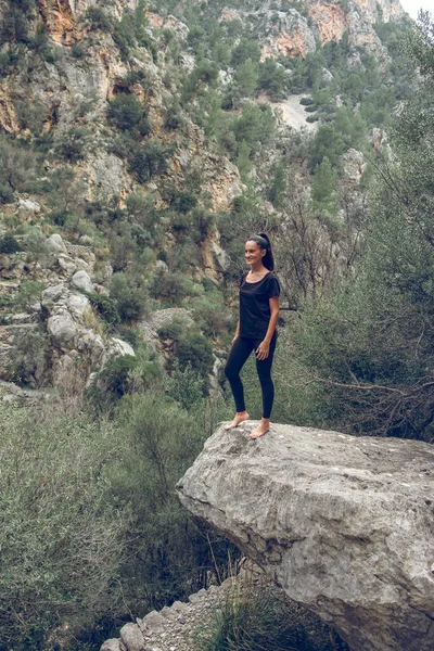 在西班牙马略卡岛的高地 穿着黑色衣服的赤脚女游客站在山脉和灌木丛的石堆上 — 图库照片