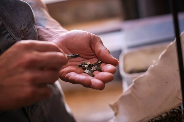 昼間の専門溶接ワークショップでの作業中に小さな金属片を保持している作物認識できない男性労働者 — ストック写真