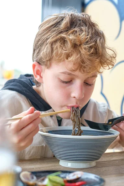Menino Comendo Macarrão Soba Saboroso Com Pauzinhos Enquanto Almoça Com — Fotografia de Stock