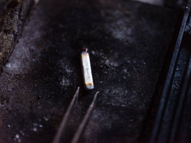 Yukarıdan seçici cımbız odağı siyah yüzeydeki küçük metal parçasına karşı