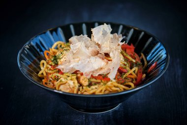 Etli soslu ve sebzeli iştah açıcı şehriye, cipsli kasede servis edilir ve siyah masaya yerleştirilir.