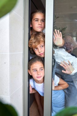 Garip, sevimli, konsantre çocuklar, günlük giysiler içinde dikilip, cam kapıya yaslanıyorlar.