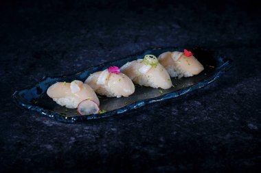 Lezzetli nigiri sushi taze baharatlı çiçek yeşil okro ve kırmızı biber ile mermer tabakta çiğ balık.