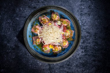 Üst düzey albacore ton balığı dilimleri. Dilimlenmiş daikon turplu. Seramik tabakta servis ediliyor.