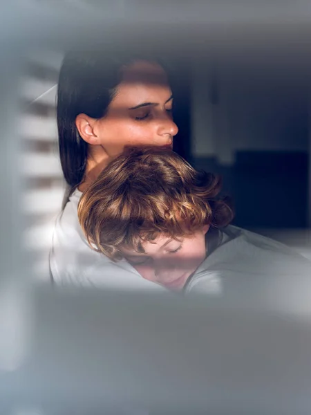 太陽の下で母親の肩に寝ている疲れ果てた小さな男の子のガラス窓を通して — ストック写真