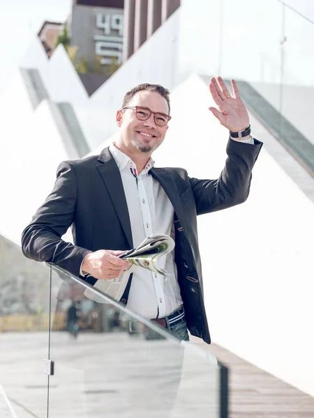 Glimlachende Mannelijke Ondernemer Met Krant Stad Straat Zwaaiende Hand Terwijl — Stockfoto