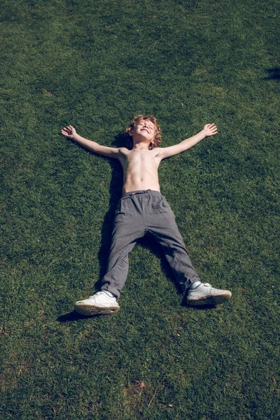 从上面 满身都是赤身裸体躺在绿草上伸展着胳膊和腿的心满意足的孩子 — 图库照片