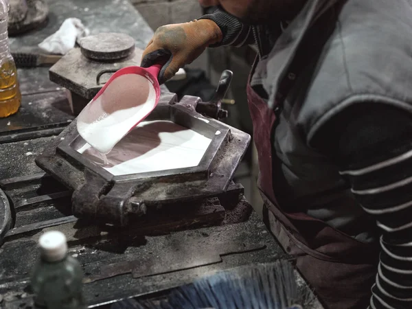 工場でセラミックタイルを製造するための金属金属金型に白セラミックを注ぎながら 保護手袋で匿名の男性職人を収穫する高角度 — ストック写真