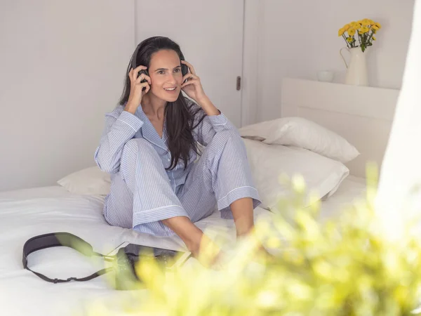 Delightful Female Sleepwear Sitting Bed Alone Holding Headphones While Listening — Stock Photo, Image
