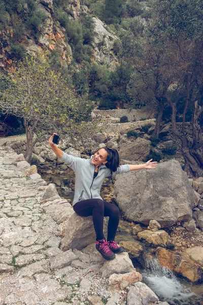 Yürüyüş Sırasında Nehir Kenarındaki Kayanın Üzerinde Oturmuş Cep Telefonuyla Selfie — Stok fotoğraf