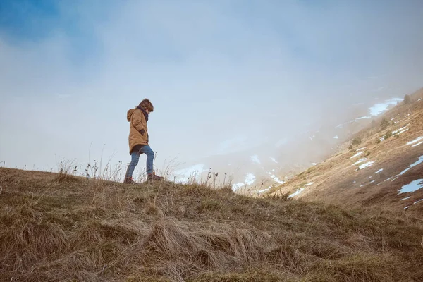 温かい服を着た男の子の完全なボディサイドビュー 自然の中で霜で山の斜面近くの草原のフィールドを散策 — ストック写真