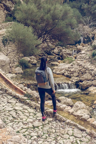 在参观Mallorca Soller Biniaraix时 背负背包的匿名女旅行家欣赏石山瀑布流水的美景 — 图库照片