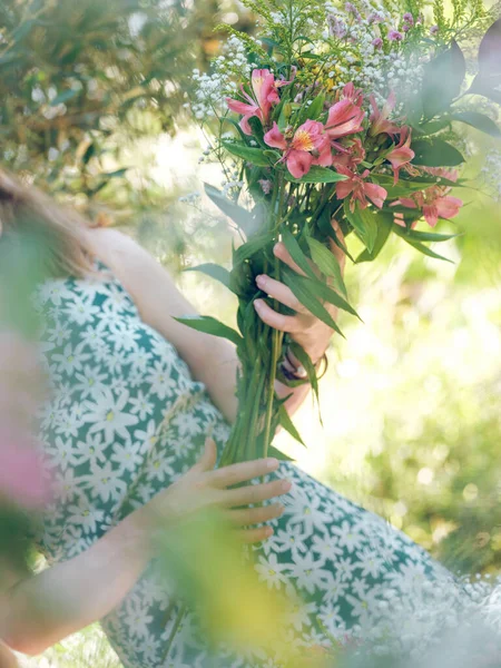 日光の中で緑の庭に立っている間 新鮮な花の創造的な花束を保持するドレスの顔の認識できない女性 — ストック写真