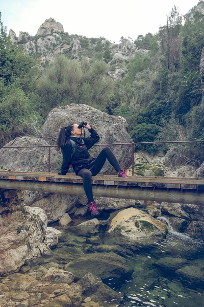 在马略卡山区的山谷中 一群身穿休闲装 长发的年轻女旅行家坐在人行天桥上 双目欣赏大自然 — 图库照片