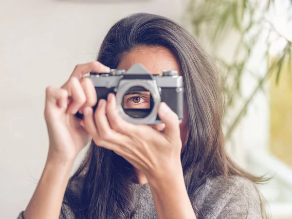 Tanımlanamayan esmer, fotoğraf çekiyormuş gibi yapıp kameraya bakarken klasik analog fotoğraf makinesi merceği için delikten bakıyor.