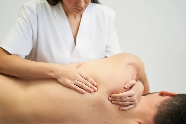 physiotherapist treating the patient\'s shoulder