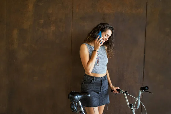 Lächelnde Frau Telefoniert Auf Fahrrad Vor Rostiger Wand — Stockfoto