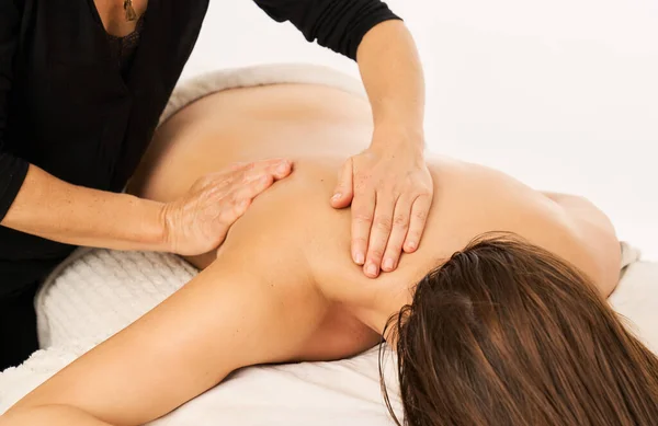 A masseuse massaging the shoulder of a woman with a shoulder injury