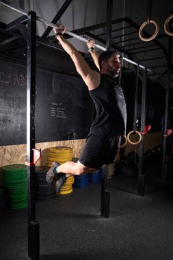 Modern spor salonunda antrenman yaparken barda egzersiz yapan güçlü erkek sporcularla dolu bir vücut.