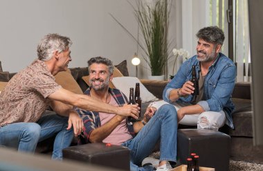 Gülümseyen yetişkin kardeşler ve olgun baba bira şişelerini tokuşturup, hafta sonları dinlenirken birbirlerine bakıyorlar.